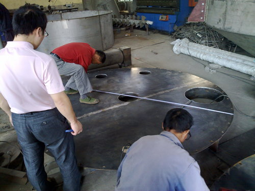 Workers measuring cut rubber sheets in a workshop